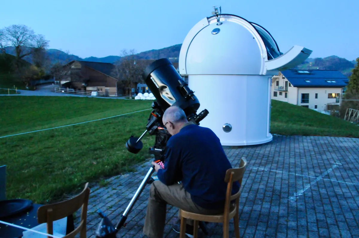 Man sieht einen Hobby-Astronomen, der sein Teleskop einrichtet.